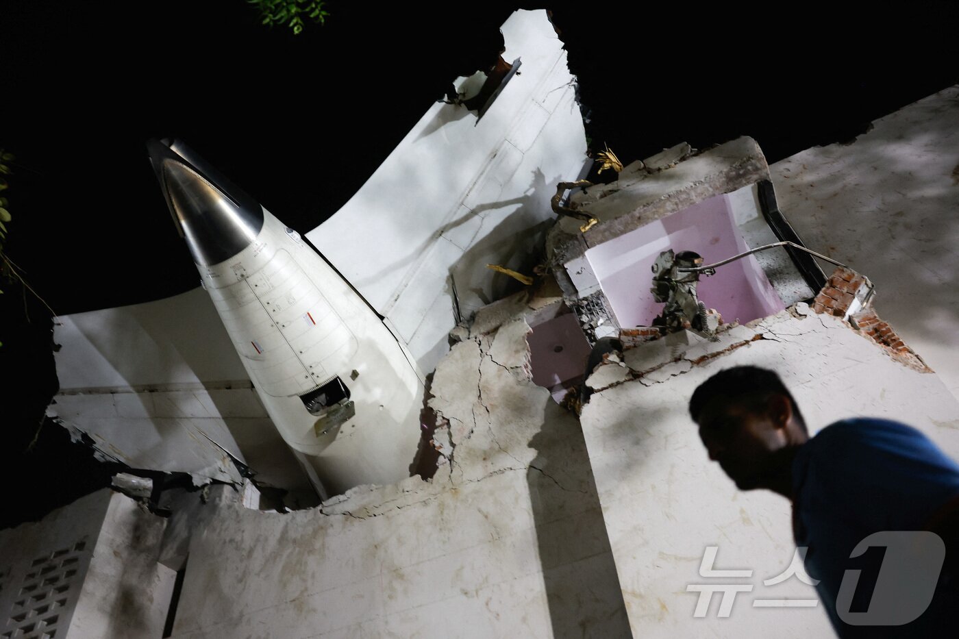 본문 이미지 - 인도 에어인디아 소속 보잉 787드림라이너 여객기가 12일&#40;현지시간&#41; 인도 서부 아메다바드 공항 인근에서 추락했다. 사진은 추락한 건물 꼭대기에 기체 꼬리가 박힌 모습. 2025.06.12 ⓒ 로이터=뉴스1 ⓒ News1 최종일 선임기자