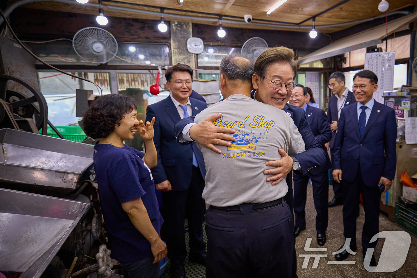 (서울=뉴스1) = 이재명 대통령이 지난 13일 경기 연천군의 한 방앗간에서 기본소득 실시지역 현황을 점검하며 주인과 포옹하고 있다.  (이재명 대통령 SNS 캡처. 재판매 및 D …