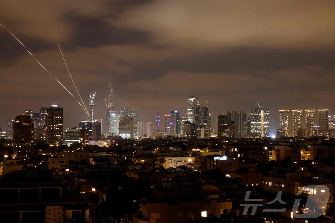 2025년 6월 15일, 이란의 로켓이 이스라엘 텔아비브 상공에서 발사된 가운데 이스라엘 방공 시스템이 가동되어 이란의 미사일을 요격하고 있다.ⓒ AFP=뉴스1