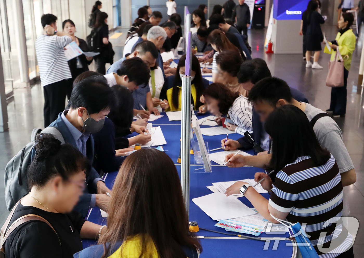 (부산=뉴스1) 윤일지 기자 = 16일 오후 부산 해운대구 벡스코 제1전시장 컨벤션홀에서 열린 '2025 해운대구 일자리박람회'에서 구직자들이 참가 신청서를 작성하고 있다.구직자와 …