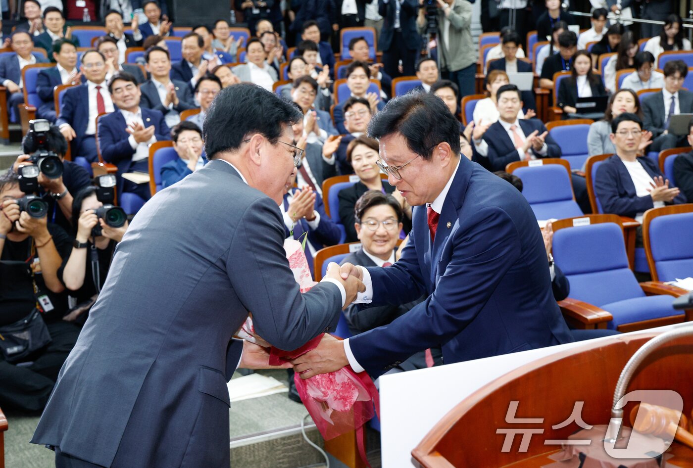 본문 이미지 - 국민의힘 신임 원내대표로 선출된 송언석 의원(왼쪽)이 16일 오후 서울 여의도 국회에서 열린 의원총회에서 박형수 선관위원장으로부터 꽃다발을 받고 있다. 2025.6.16/뉴스1 ⓒ News1 안은나 기자