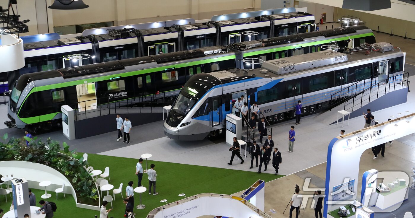 본문 이미지 - 18일 부산 해운대구 벡스코 제1전시장에서 열린 &#39;2025 부산국제철도기술산업전&#39;에서 관람객들이 현대로템의 공항철도 전동차, 대만 그린라인 무인전동차, 캐나다 에드먼턴 밸리라인 웨스트 트램 실물을 둘러보고 있다.  2025.6.18/뉴스1 ⓒ News1 윤일지 기자