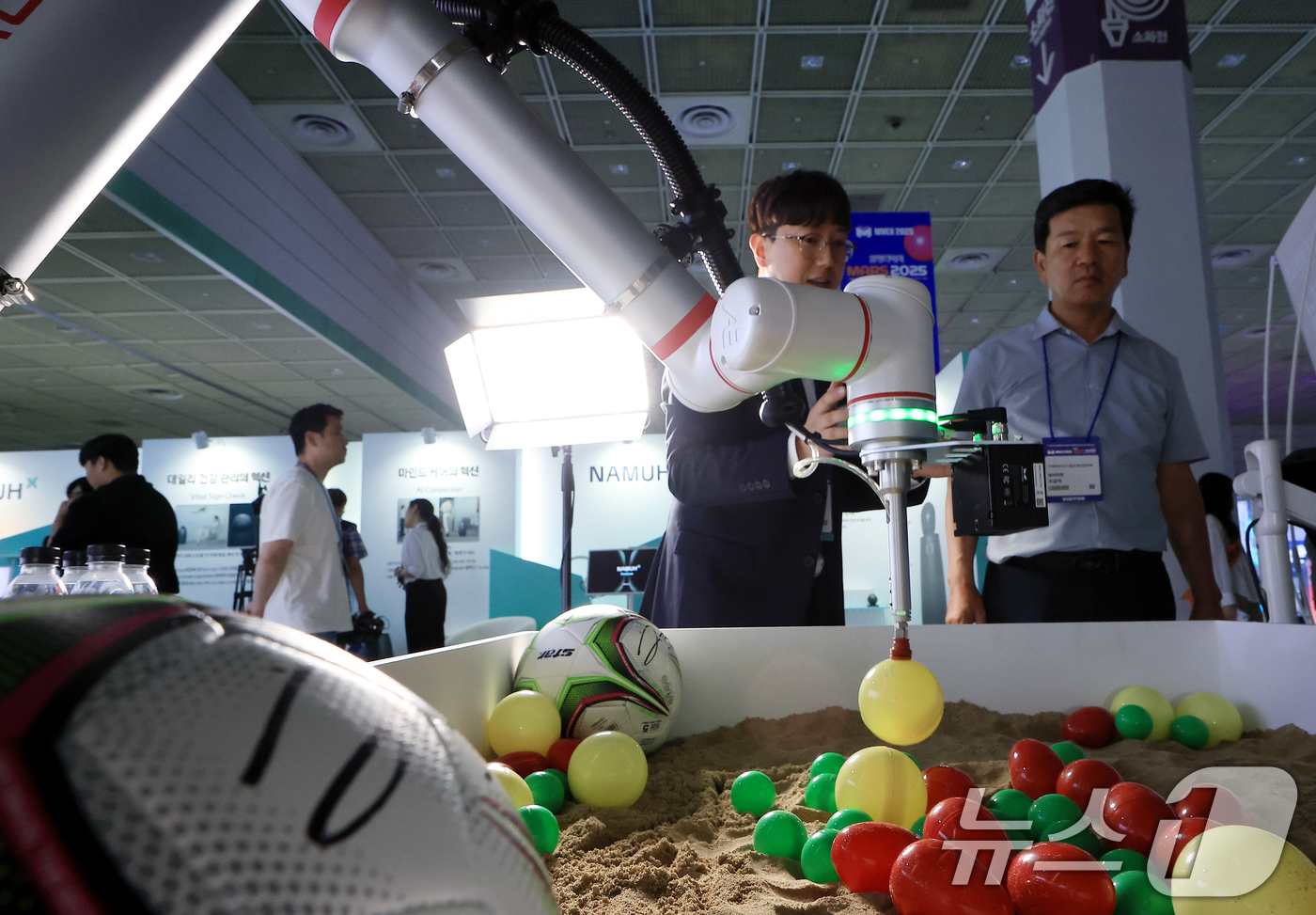 (서울=뉴스1) 박정호 기자 = 18일 서울 강남구 삼성동 코엑스에서 열린 2025 메타버스 엑스포를 찾은 참관객이 아비만 협동로봇의 딥러닝 캡슐뽑기를 지켜보고 있다.  2025. …