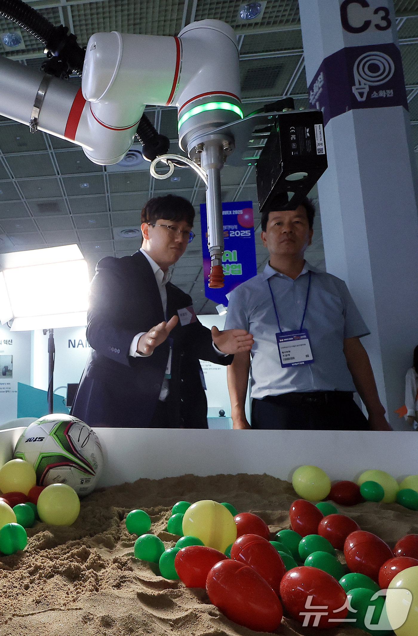 (서울=뉴스1) 박정호 기자 = 18일 서울 강남구 삼성동 코엑스에서 열린 2025 메타버스 엑스포를 찾은 참관객이 아비만 협동로봇의 딥러닝 캡슐뽑기를 지켜보고 있다.  2025. …