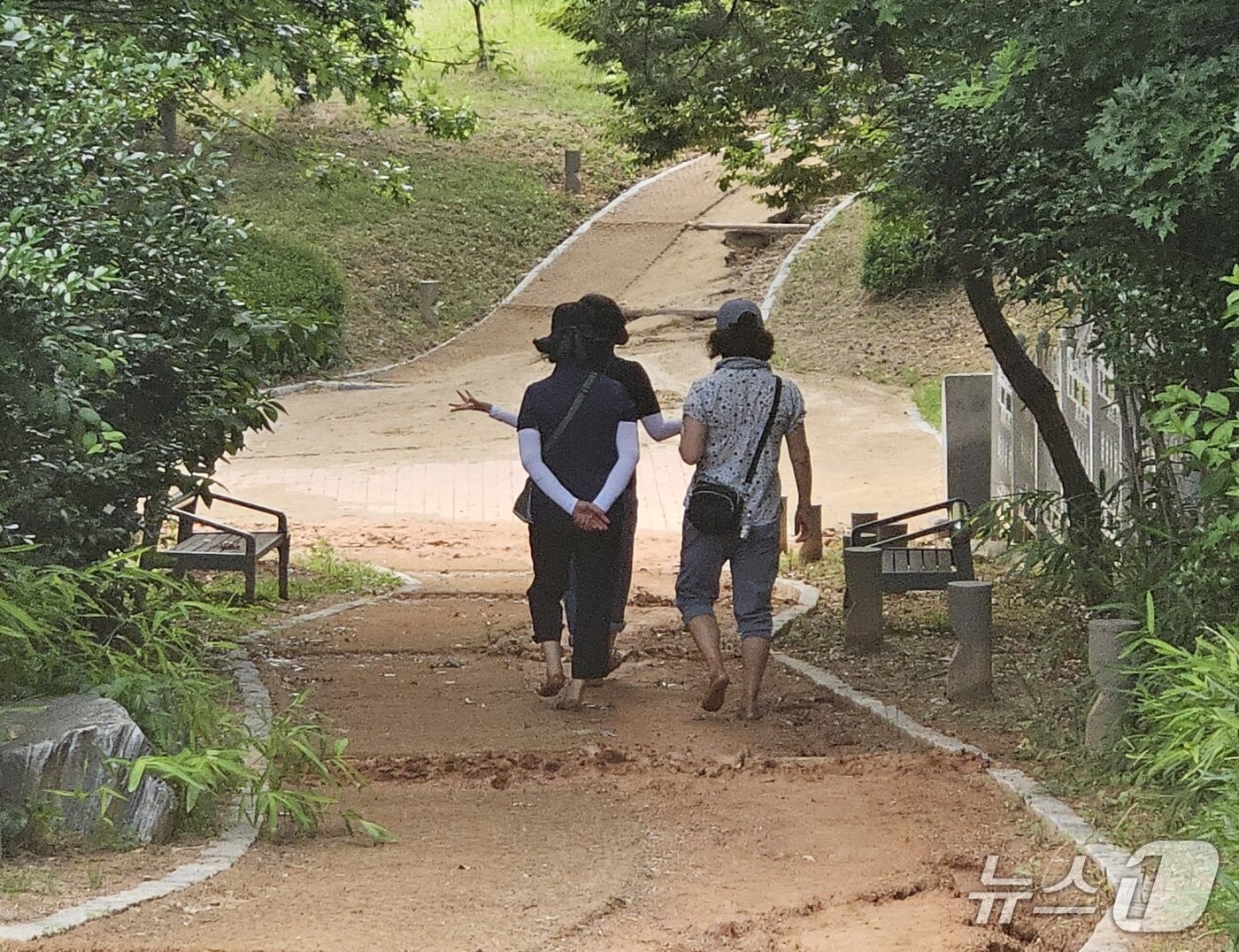 본문 이미지 -  빗물로 일부 구간이 유실된 전북 전주 효열·솔바람공원 맨발길을 이용 중인 시민들. 2025.6.17/신준수 기자