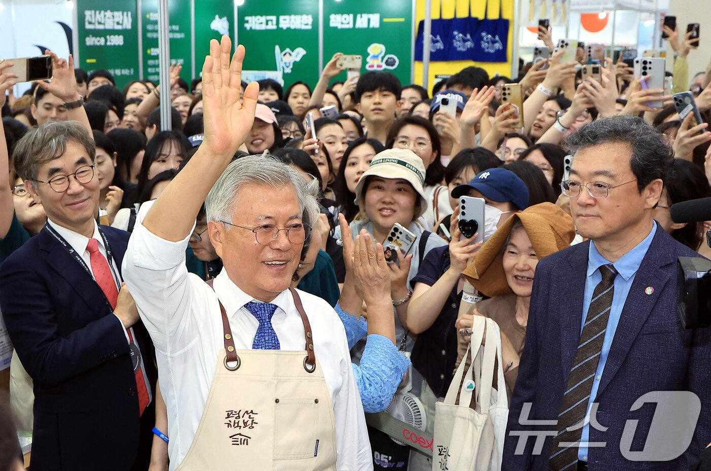 본문 이미지 - 문재인 전 대통령이 18일 오후 서울 강남구 삼성동 코엑스에서 열린 2025 서울국제도서전 평산책방 부스에서 앞치마를 두르고 나와 방문객들에게 인사하고 있다. 2025.6.18/뉴스1 ⓒ News1 박정호 기자