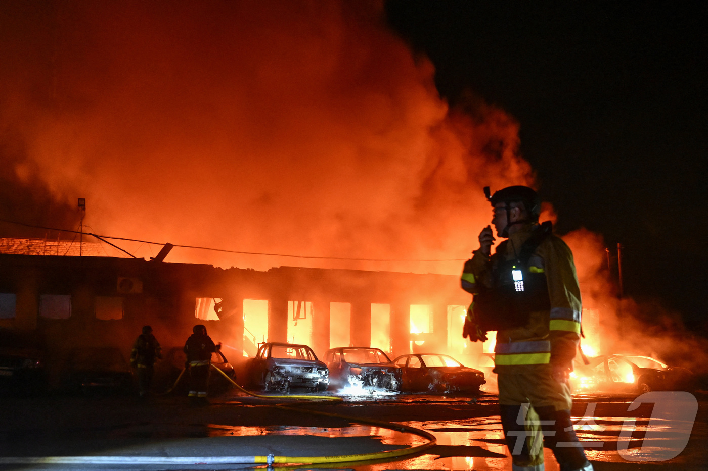 (자포리자 로이터=뉴스1) 김지완 기자 = 18일(현지시간) 우크라이나 자포리자에서 러시아의 드론 공격을 받아 불타고 있는 한 기업 건물 근처에서 소방관들이 진화 작업을 벌이고 있 …