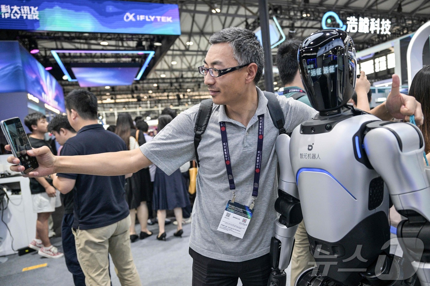 (상하이 AFP=뉴스1) 신기림 기자 = 18일 상하이 신국제엑스포센터에서 열린 모바일 월드 콩그레스(MWC)에서 한 남성이 지위안(Zhiyuan)사의 로봇(애지봇)과 셀카를 찍고 …