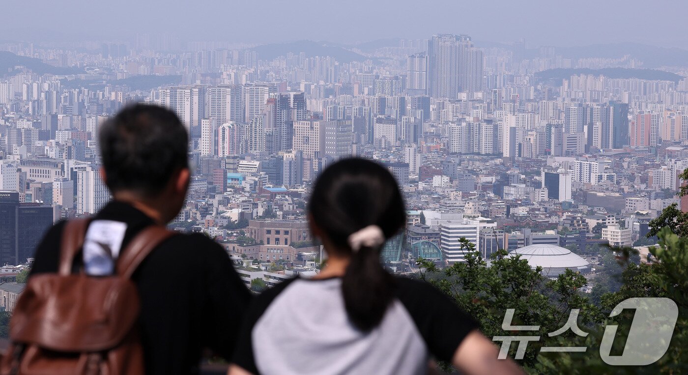 본문 이미지 - 서울 남산을 찾은 시민이 도심 아파트 단지를 바라보고 있다. 2025.6.18/뉴스1 ⓒ News1 박지혜 기자