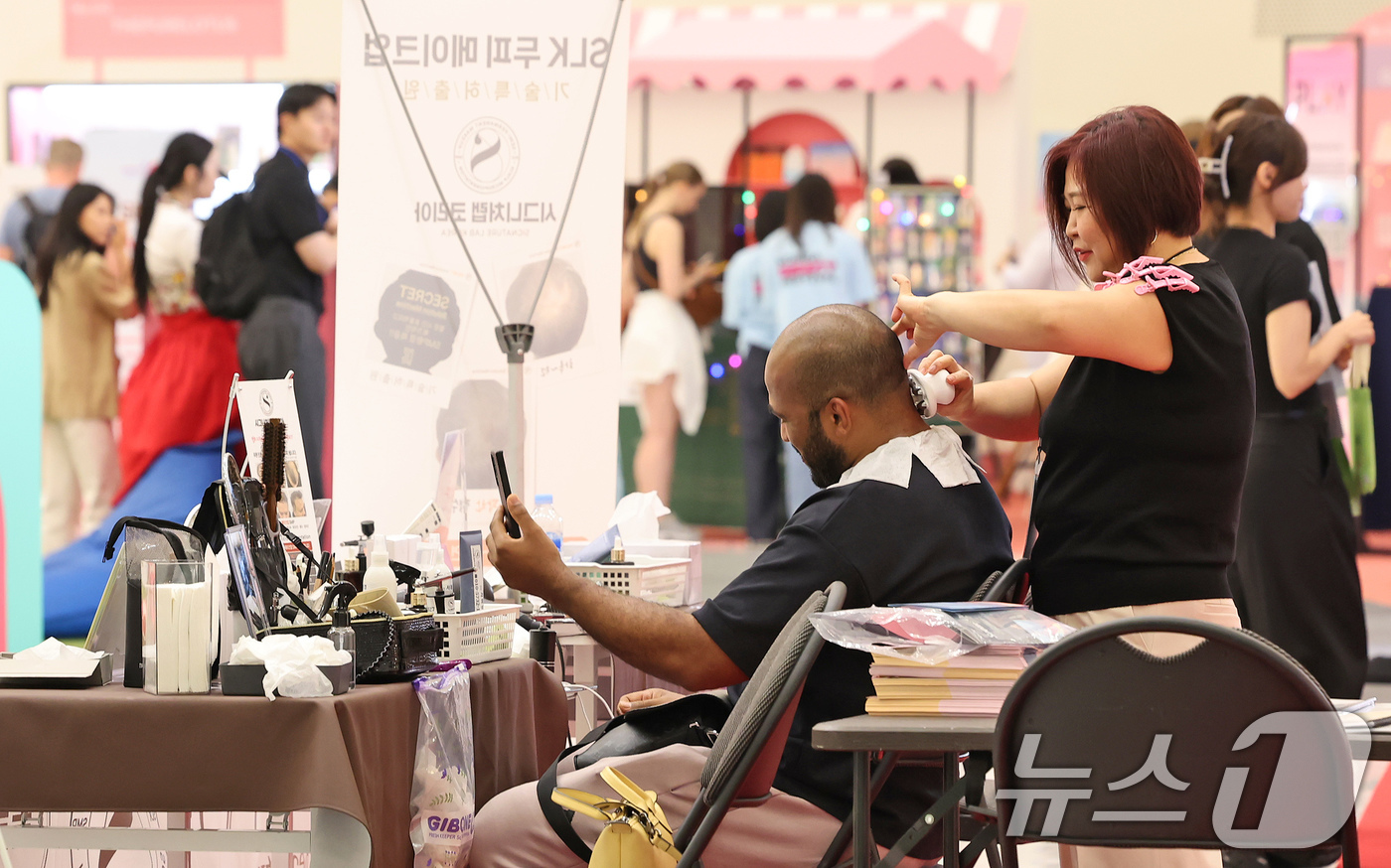 (서울=뉴스1) 장수영 기자 = 19일 오후 서울 중구 DDP에서 열린 2025 코리아뷰티페스티벌를 찾은 외국인 관광객이 두피 메이크업 제품 체험을 하고 있다. 2025.6.19/ …