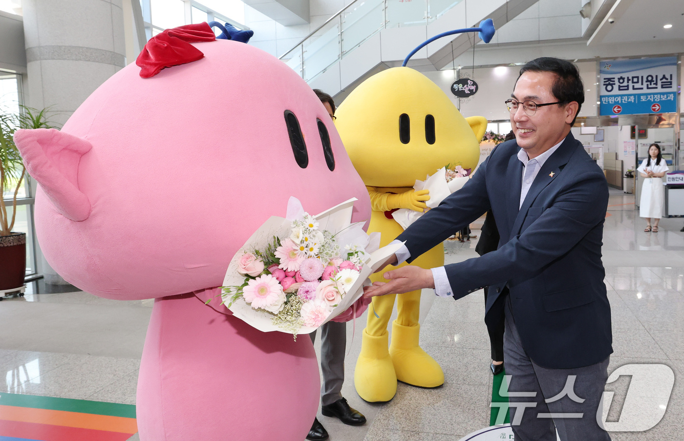 (대전=뉴스1) 김기태 기자 = 박희조 대전 동구청장이 19일 전입신고를 하기 위해 동구청을 방문한 대전시 대표 캐릭터인 꿈돌이·꿈순이에게 꽃다발을 전달하고 있다.이번 행사는 대전 …