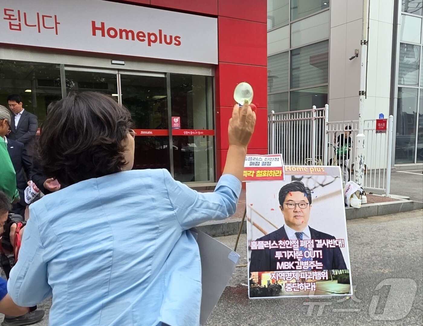 본문 이미지 - 마트 노동자들이 지난 2일 천안시 동남구 홈플러스 천안점 앞에서 열린 폐점 반대 기자회견에서 김병주 MBK파트너스 회장을 규탄하며 얼굴 사진에 물풍선을 던지고 있다. 2025.6.2/뉴스1 ⓒ News1 이시우 기자