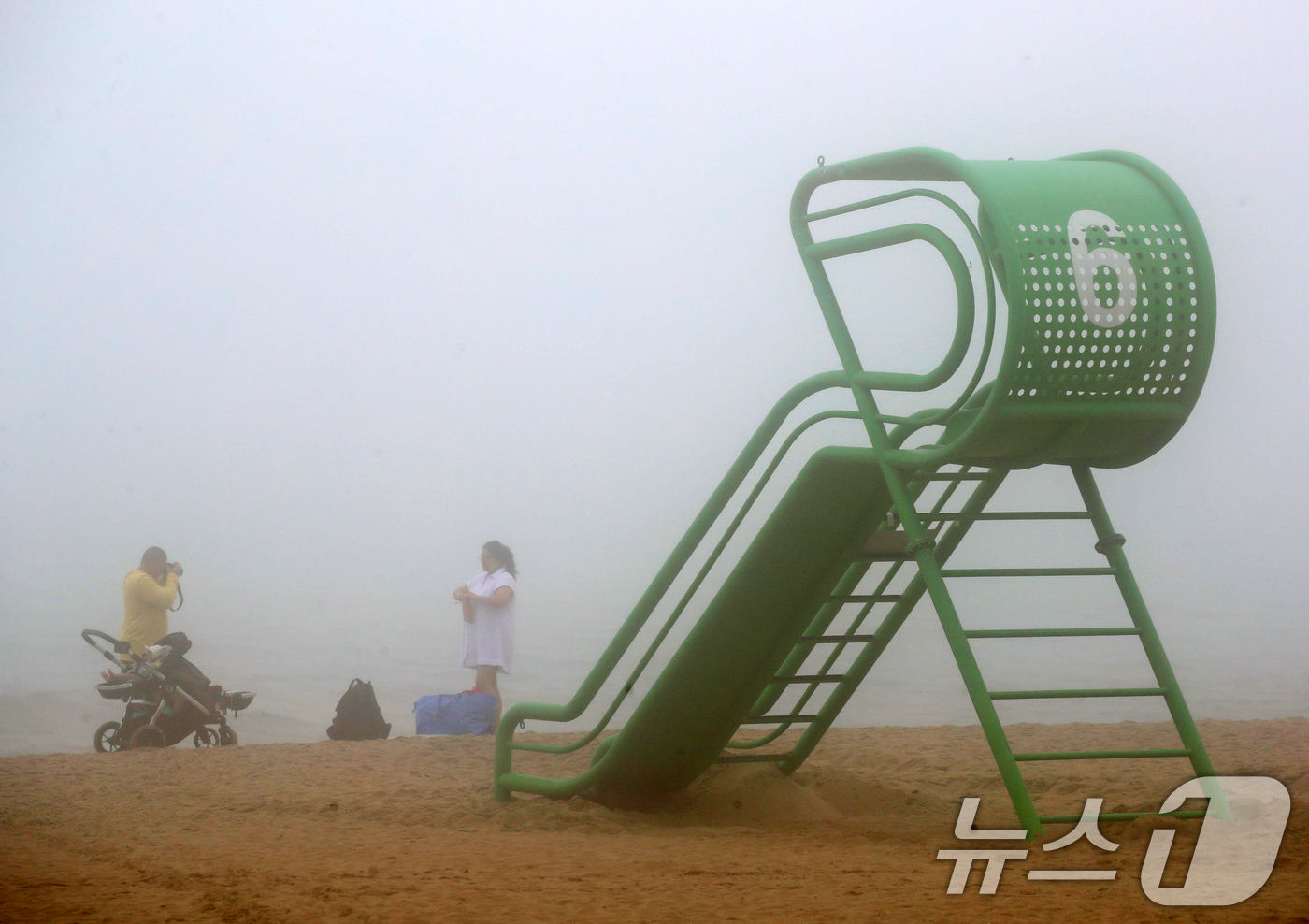 (부산=뉴스1) 윤일지 기자 = 20일 부산 해운대해수욕장에 설치된 망루 옆으로 관광객들이 안개가 낀 바다를 배경으로 사진을 찍고 있다.부산 해운대·송정해수욕장은 오는 21일 개장 …
