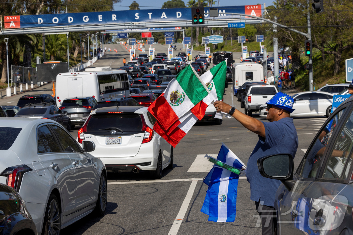 (LA 로이터=뉴스1) 신기림 기자 = 19일(현지시간) 미국 캘리포니아주 로스앤젤레스의 다저스타디움 A게이트 밖에서 한 상인이 멕시코와 살바도르 국기를 판매하고 있다. 이날 LA …
