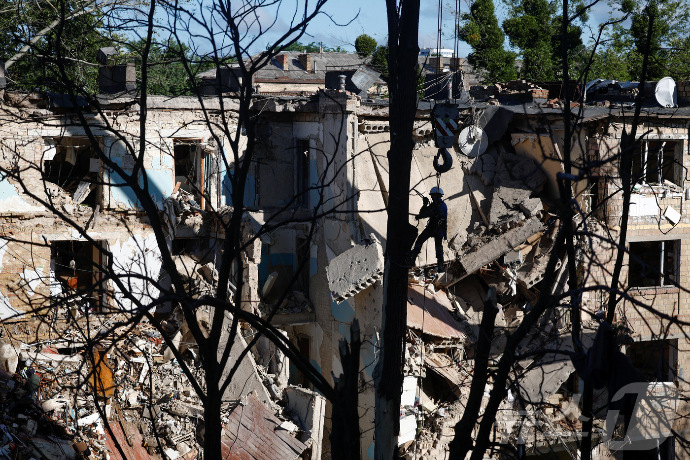 (키이우 로이터=뉴스1) 권영미 기자 = 러시아의 드론과 미사일 공격을 받은 한 손상된 아파트 건물에 구조대원이 아슬아슬하게 서 있다. 2025.06.23.ⓒ 로이터=뉴스1