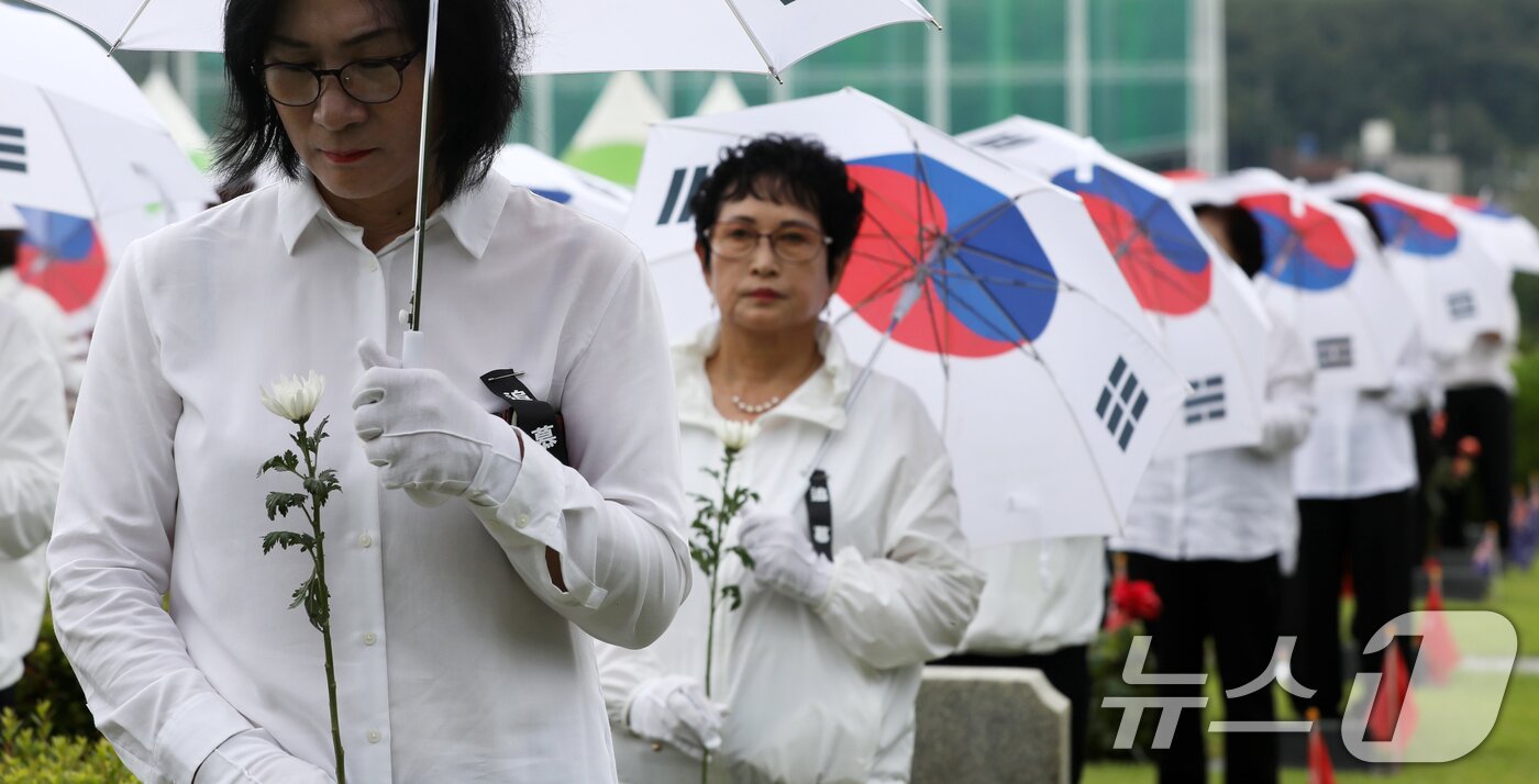 본문 이미지 - 25일 오전 부산 남구 유엔기념공원에서 열린 제75주년 6·25전쟁 참전 유엔전몰용사 추모제에서 태극기 우산을 쓴 참석자들이 유엔군 전몰장병 묘역을 참배하고 있다. 2025.6.25/뉴스1 ⓒ News1 윤일지 기자