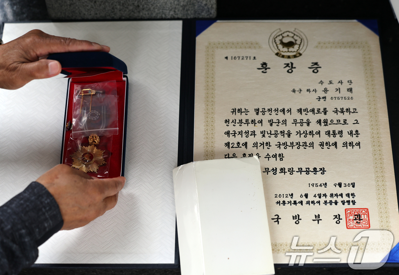 (서울=뉴스1) 황기선 기자 = 6·25전쟁 75주년인 25일 서울 용산구 전쟁기념관에서 참전용사 유가족이 명비 앞에서 무공훈장과 훈장증을 놓고 있다. 2025.6.25/뉴스1