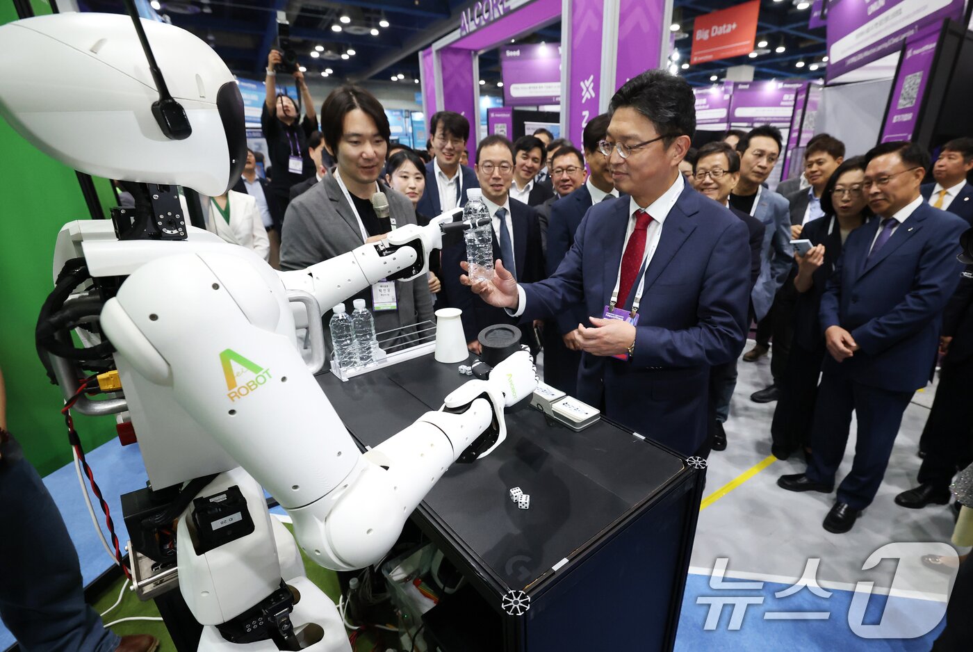 본문 이미지 - 26일 서울 강남구 코엑스에서 막을 올린 &#39;넥스트라이즈 2025&#39;에서 에이로봇의 이족보행 휴머노이드 로봇 앨리스4가 참관객들에게 물을 건네고 있다. 2025.6.26/뉴스1 ⓒ News1 오대일 기자