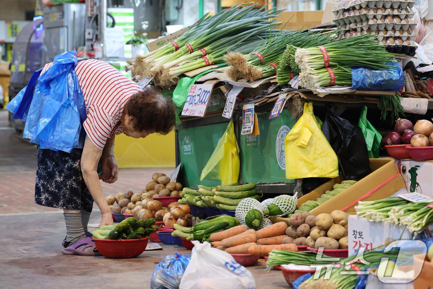 본문 이미지 -  서울의 한 전통시장에서 한 상인이 비닐봉투를 허리에 두른 채 장사 준비를 하고 있다. 2025.6.26/뉴스1 ⓒ News1 신웅수 기자
