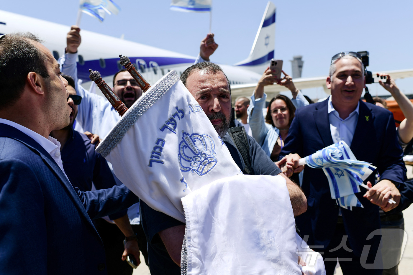 (벤구리온 로이터=뉴스1) 김지완 기자 = 25일(현지시간) 이스라엘에서의 새 삶을 시작하려고 돌아온 유럽의 유대인 이민자가 벤구리온 국제공항에 도착한 이후 유대교의 율법 두루마리 …
