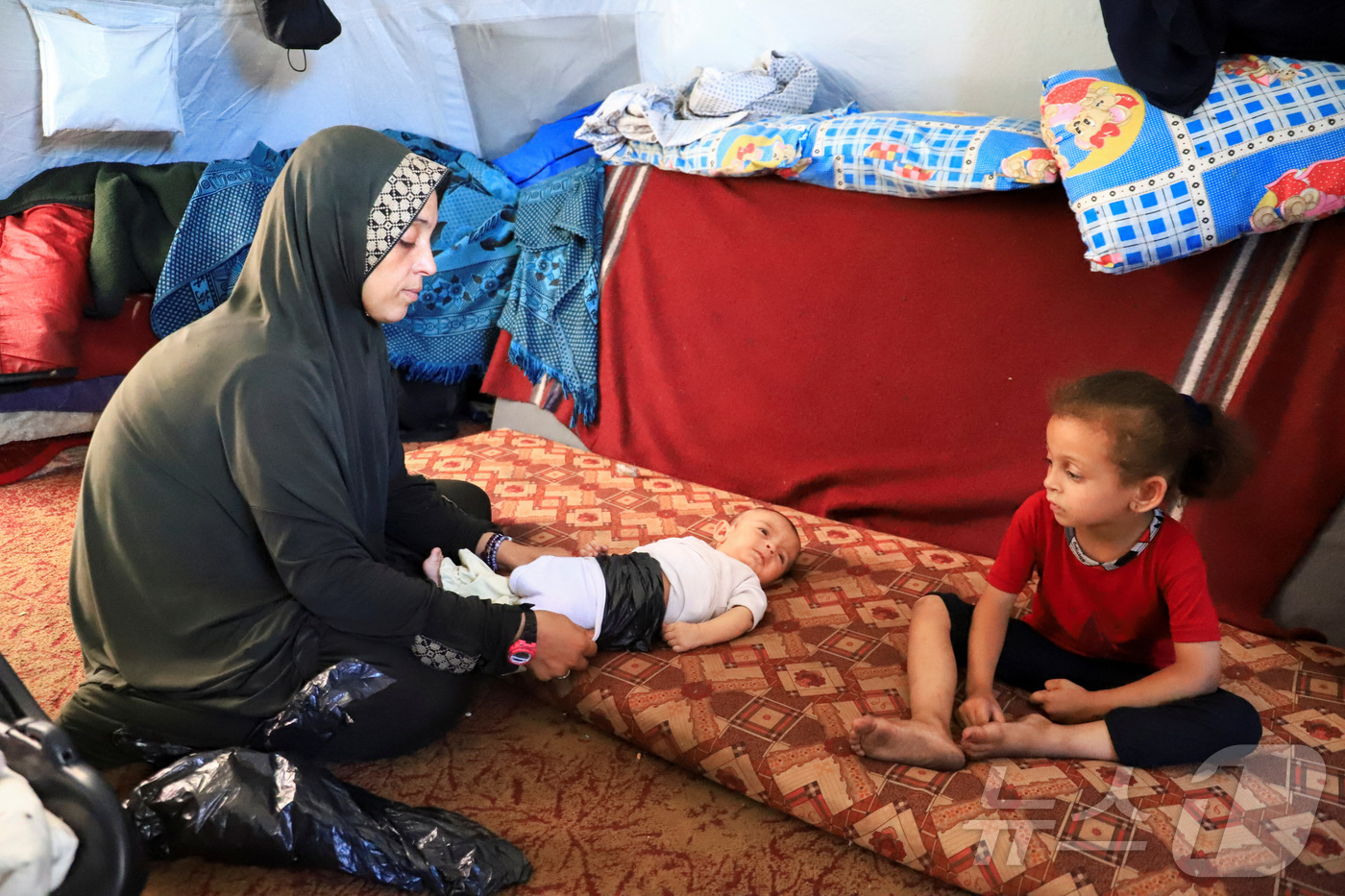 (가자시티 로이터=뉴스1) 권영미 기자 = 25일(현지시간) 팔레스타인 가자 지구의 한 어머니가 2개월된 쌍둥이 중 한 명을 수심에 찬 얼굴로 바라보고 있다. 가자 지구는 분유와 …