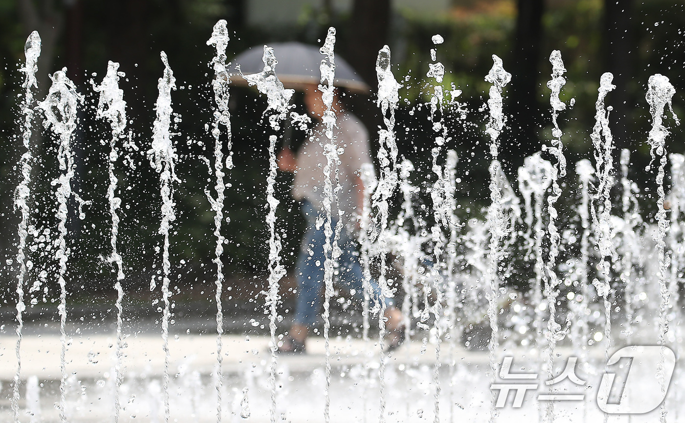 (대구=뉴스1) 공정식 기자 = 대구·경북에 올여름 첫 폭염주의보가 발효된 27일 오후 대구 서구 평리공원에서 양산을 쓴 시민이 바닥분수 옆을 지나고 있다. 2025.6.27/뉴스 …