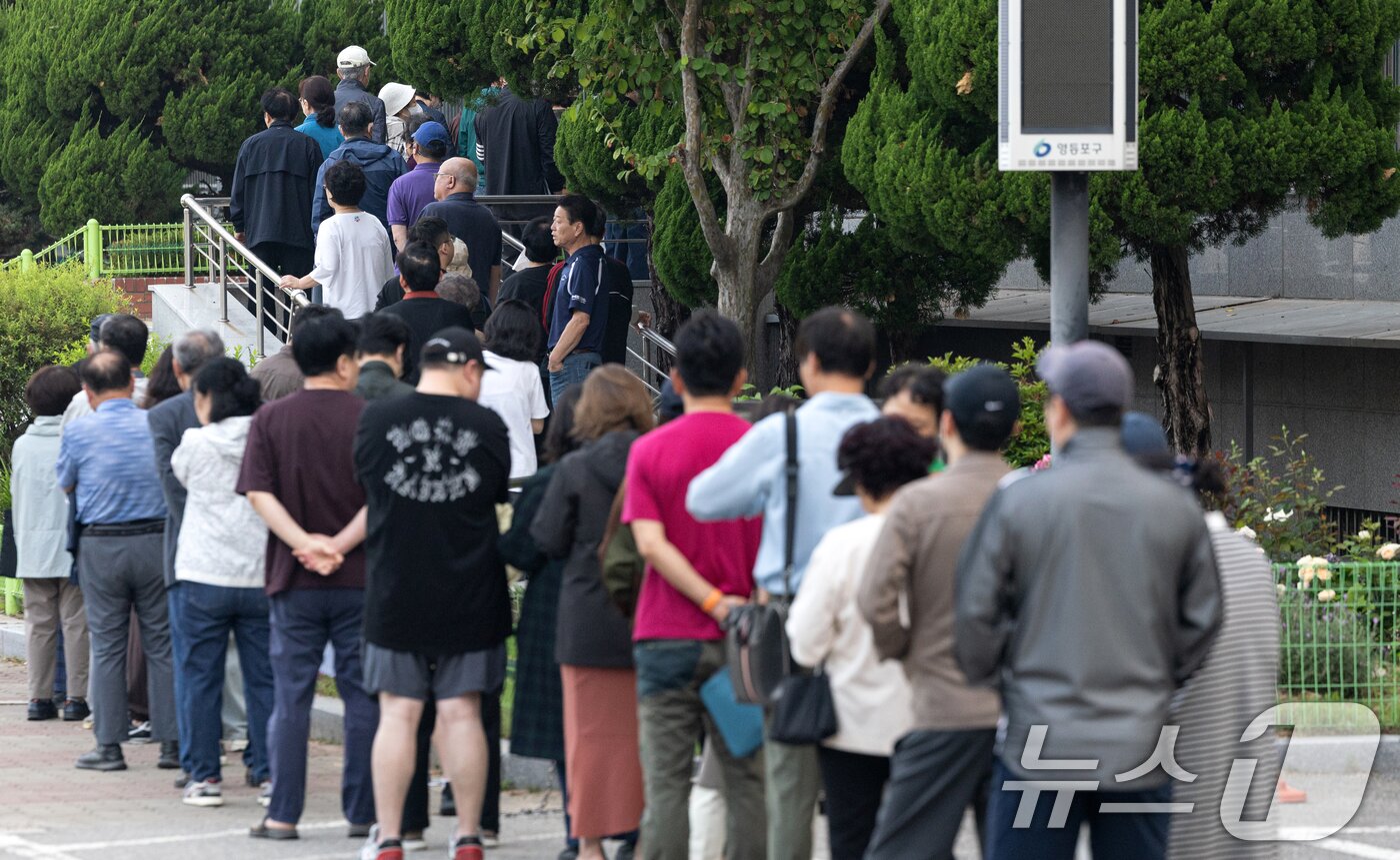 본문 이미지 - 제21대 대통령 선거일인 3일 서울 영등포구 여의도 윤중중학교에 마련된 투표소를 찾은 시민들이 길게 줄 서 있다. 2025.6.3/뉴스1 ⓒ News1 이승배 기자
