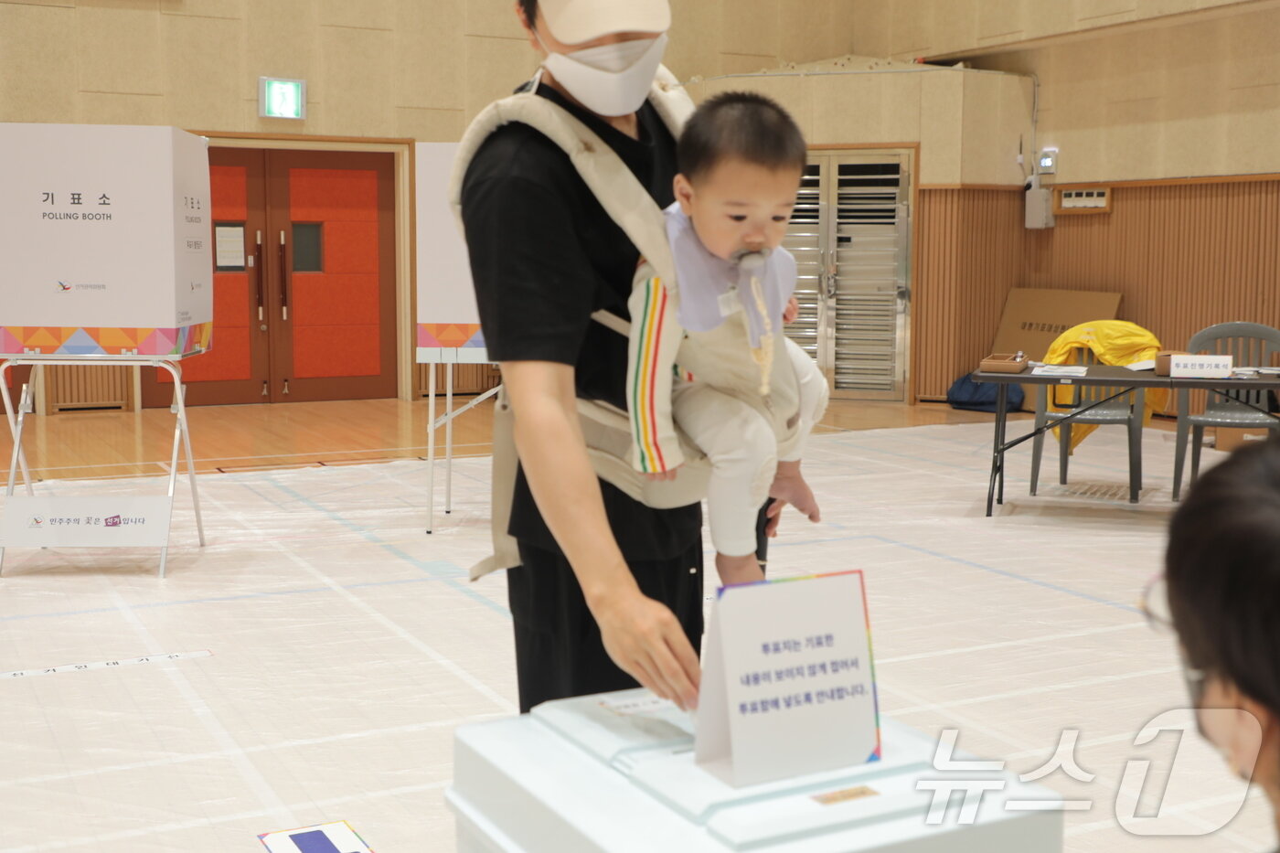 본문 이미지 - 21대 대통령선거 본투표일인 3일 울산 북구 고헌초등학교에 마련된 투표소에서 한 시민이 자녀를 안고 투표하고 있다. 2025.6.3/뉴스1 ⓒ News1 김세은 기자