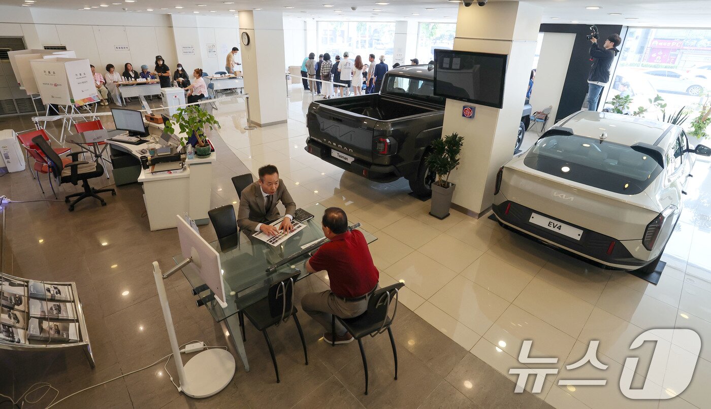 본문 이미지 - 제21대 대통령 선거일인 3일 서울 광진구 기아자동차 대공원대리점에 마련된 능동제3투표소에서 유권자들이 투표를 하고 있다. 아래쪽에 대리점 직원이 고객과 차량 구매 상담을 하고 있다. 2025.6.3/뉴스1 ⓒ News1 박세연 기자