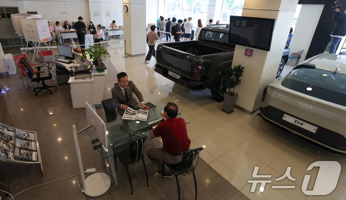 (서울=뉴스1) 박세연 기자 = 제21대 대통령 선거일인 3일 서울 광진구 기아자동차 대공원대리점에 마련된 능동제3투표소에서 유권자들이 투표를 하고 있다. 아래쪽에 대리점 직원이 …