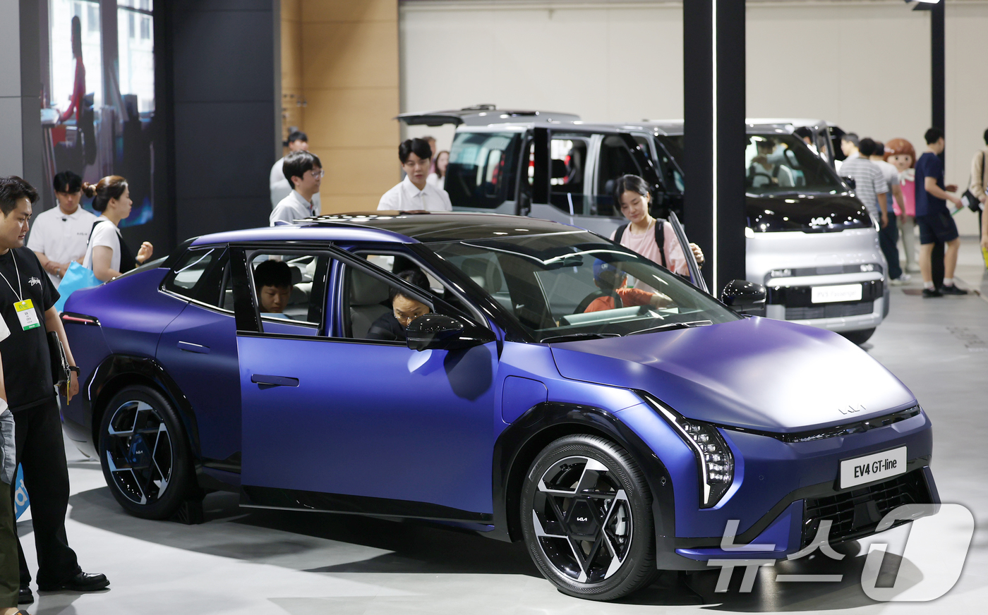 (서울=뉴스1) 오대일 기자 = 3일 오전 서울 강남구 코엑스에서 열린 'EV트렌드코리아 2025'에서 방문객들이 기아의 준중형 전동화 세단 EV4 GT-line 모델을 살펴보고 …