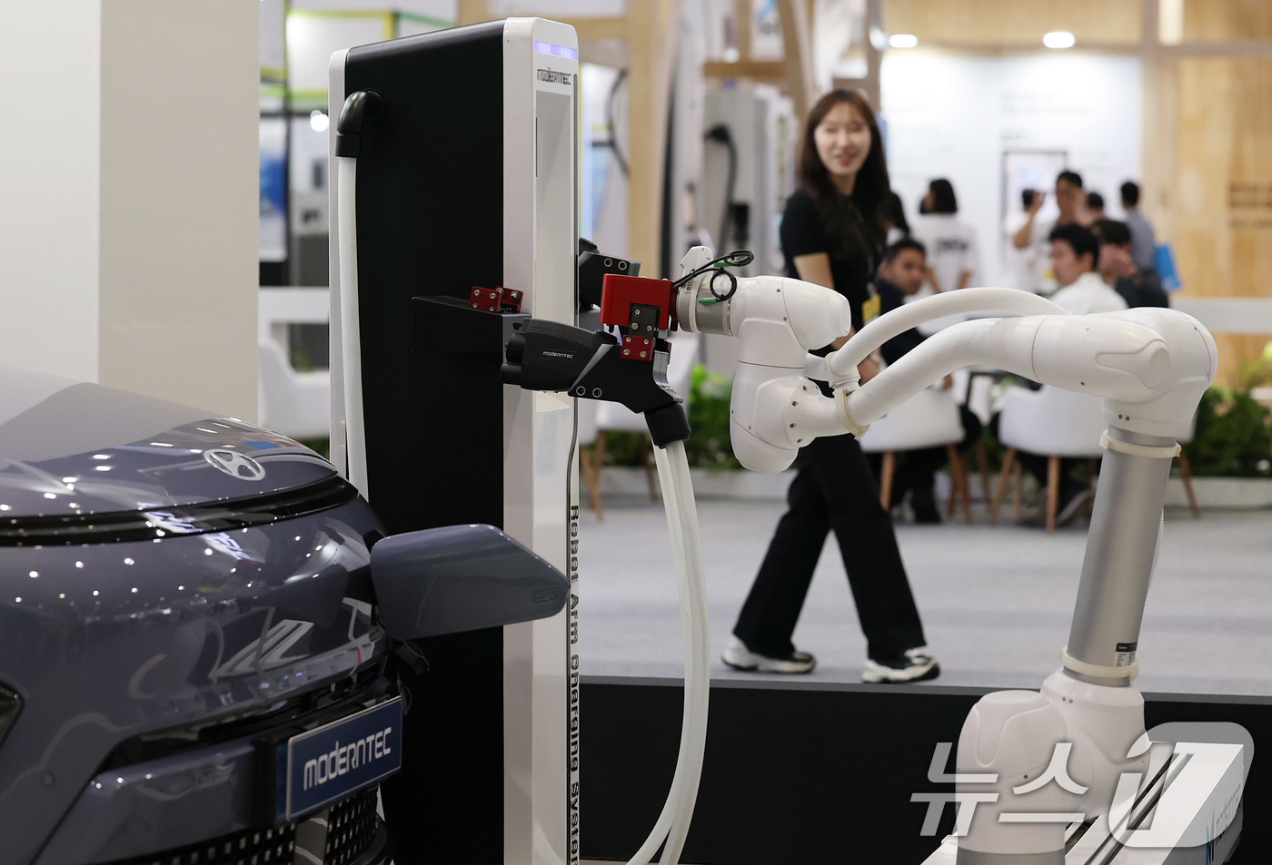 (서울=뉴스1) 오대일 기자 = 3일 오전 서울 강남구 코엑스에서 열린 'EV트렌드코리아 2025'에서 방문객들이 모던텍의 로봇 전기차 충전 시스템을 살펴보고 있다.국내 대표 전기 …