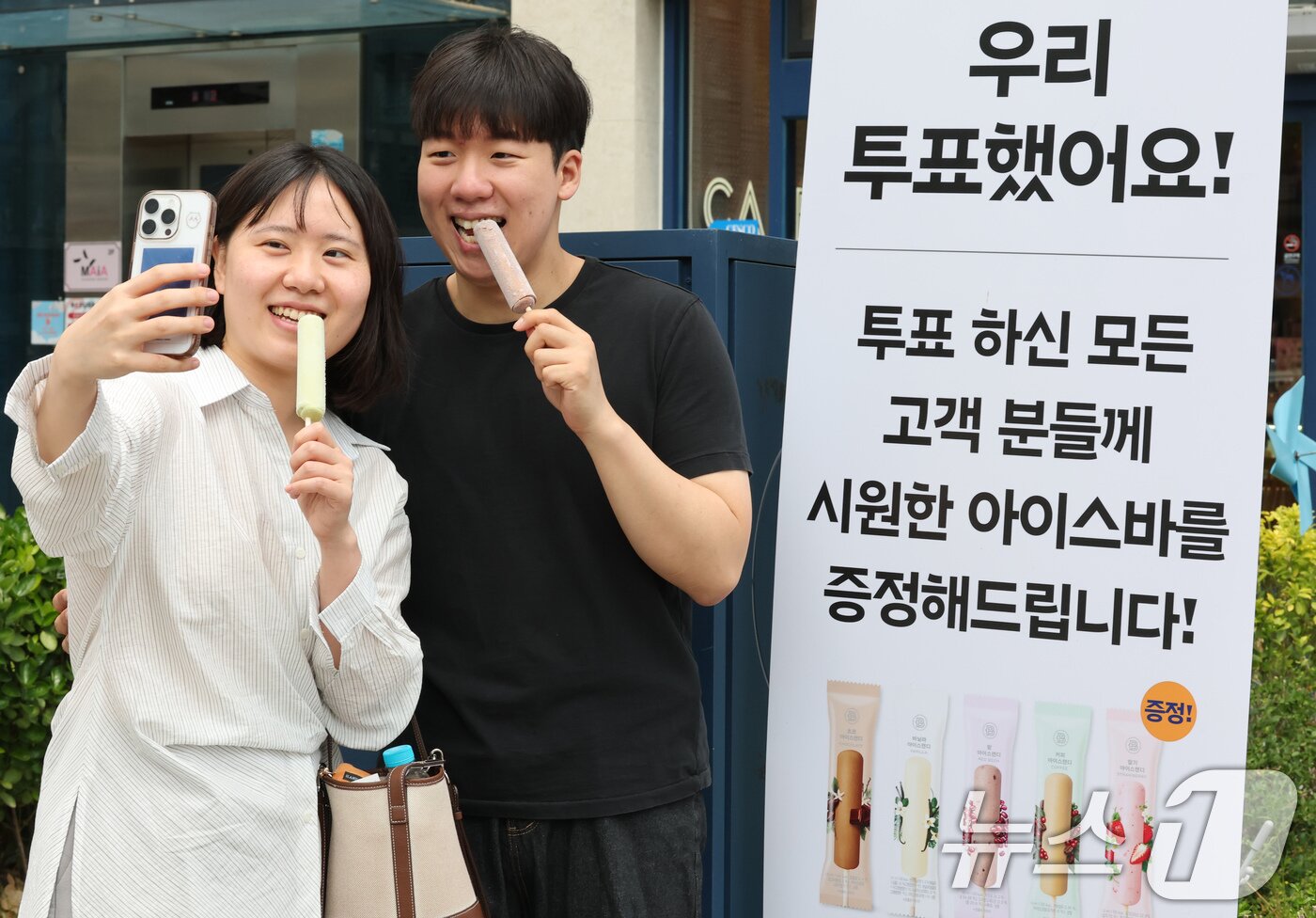 본문 이미지 - 제21대 대통령 선거일가 실시된 3일 대전 유성구 온천동 한 상가에서 투표한 유권자에게 아이스바를 증정하는 행사를 진행한 가운데 투표를 마친 유권자가 인증사진을 촬영하고 있다. 2025.6.3/뉴스1 ⓒ News1 김기태 기자