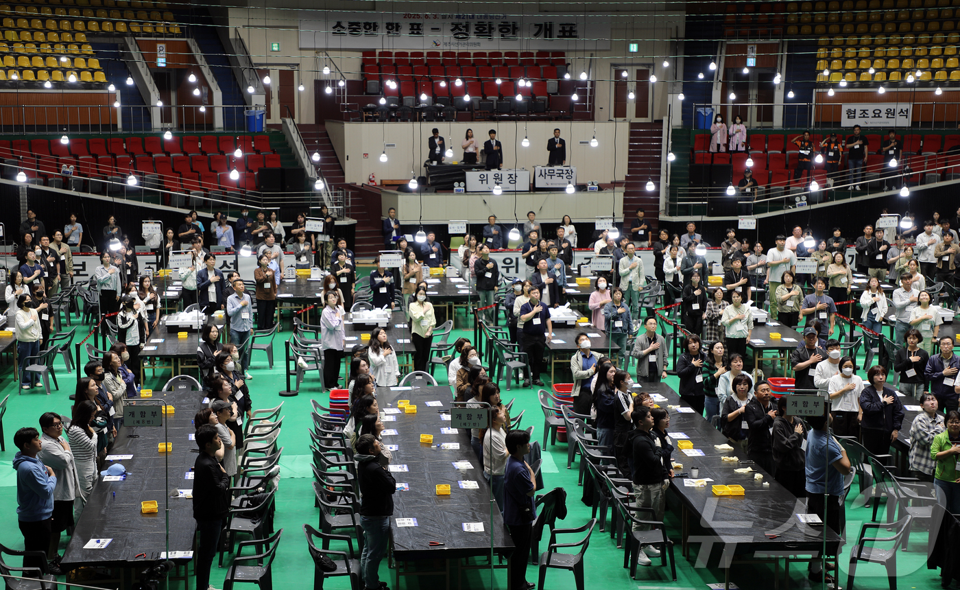 (제주=뉴스1) 오미란 기자 = 제21대 대통령 선거일인 3일 오후 제주시 개표소인 제주종합경기장 한라체육관에서 개표사무원들이 국기에 대한 경례를 하고 있다. 2025.6.3/뉴스 …