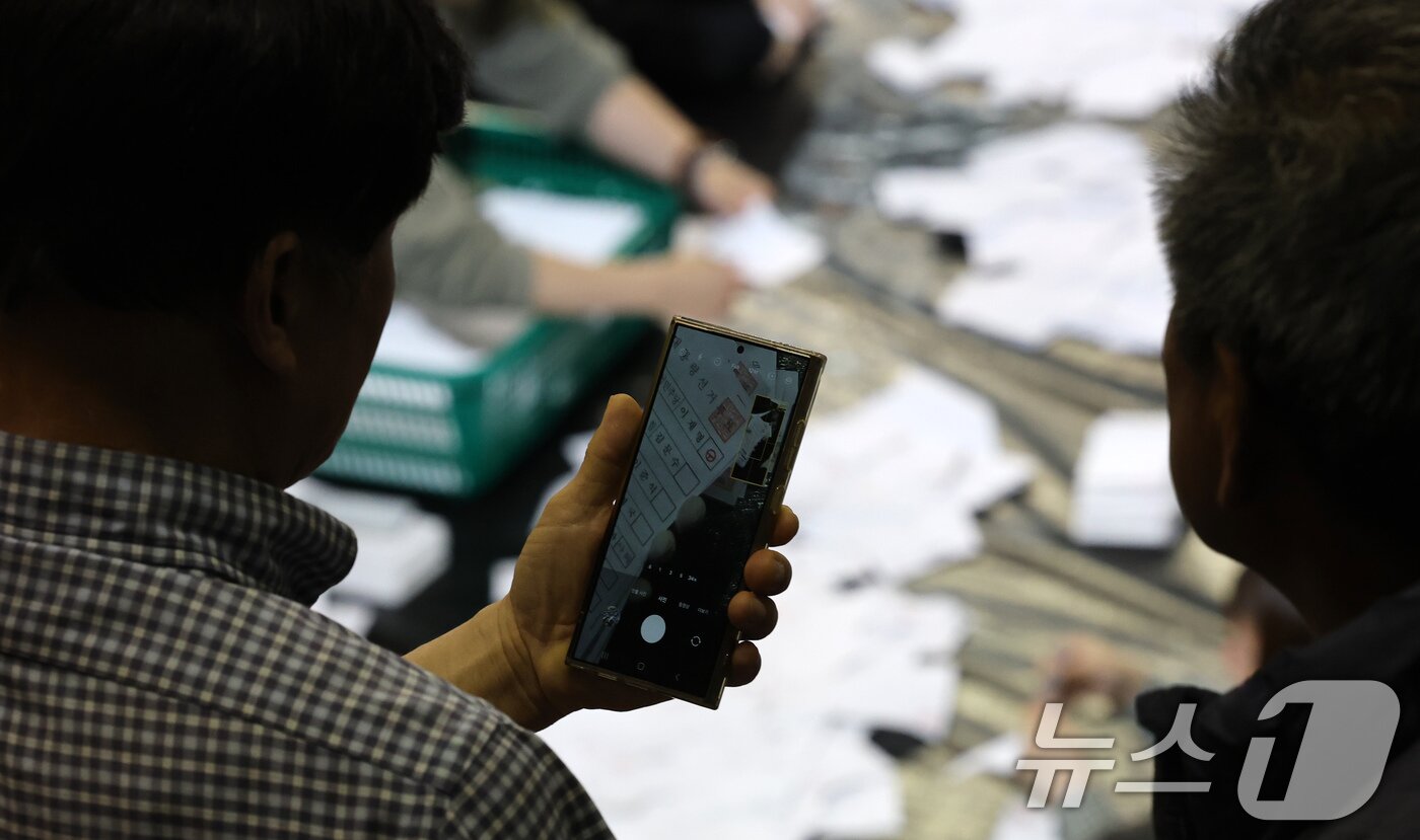 본문 이미지 - 제21대 대통령 선거 투표가 실시된 3일 대전 서구 KT인재개발원에 마련된 개표소에서 개표 관람인들이 투표용지 분류 상황을 촬영하고 있다. 2025.6.3/뉴스1 ⓒ News1 김기태 기자