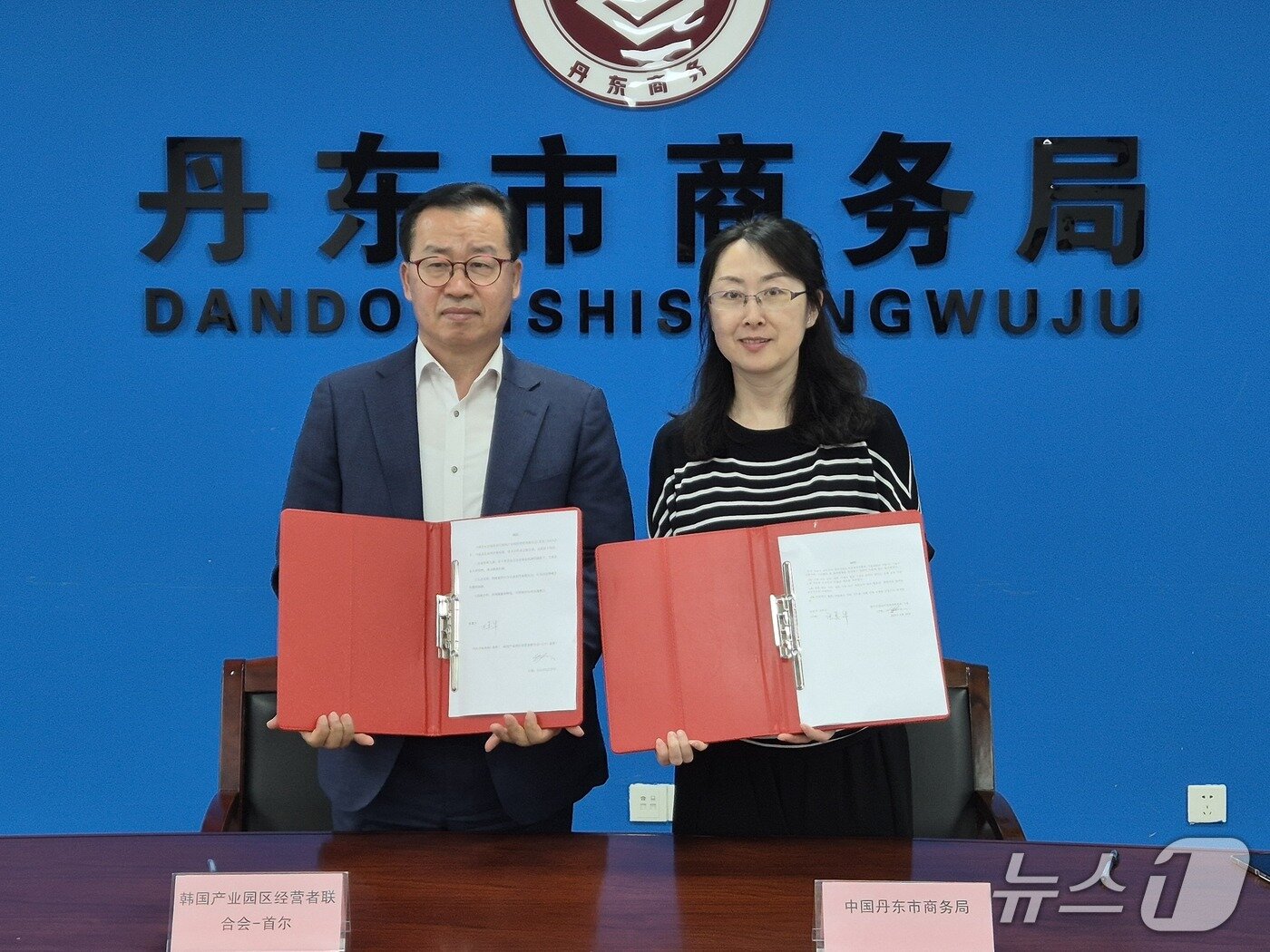본문 이미지 - 한국산업단지경영자연합회 정진한 부회장이 30일 중국 랴오닝성 단둥시정부 상무국 장메이화 국장과 한중 기업 교류에 관한 MOU를 체결한 후 양해각서를 들어보이고 있다.