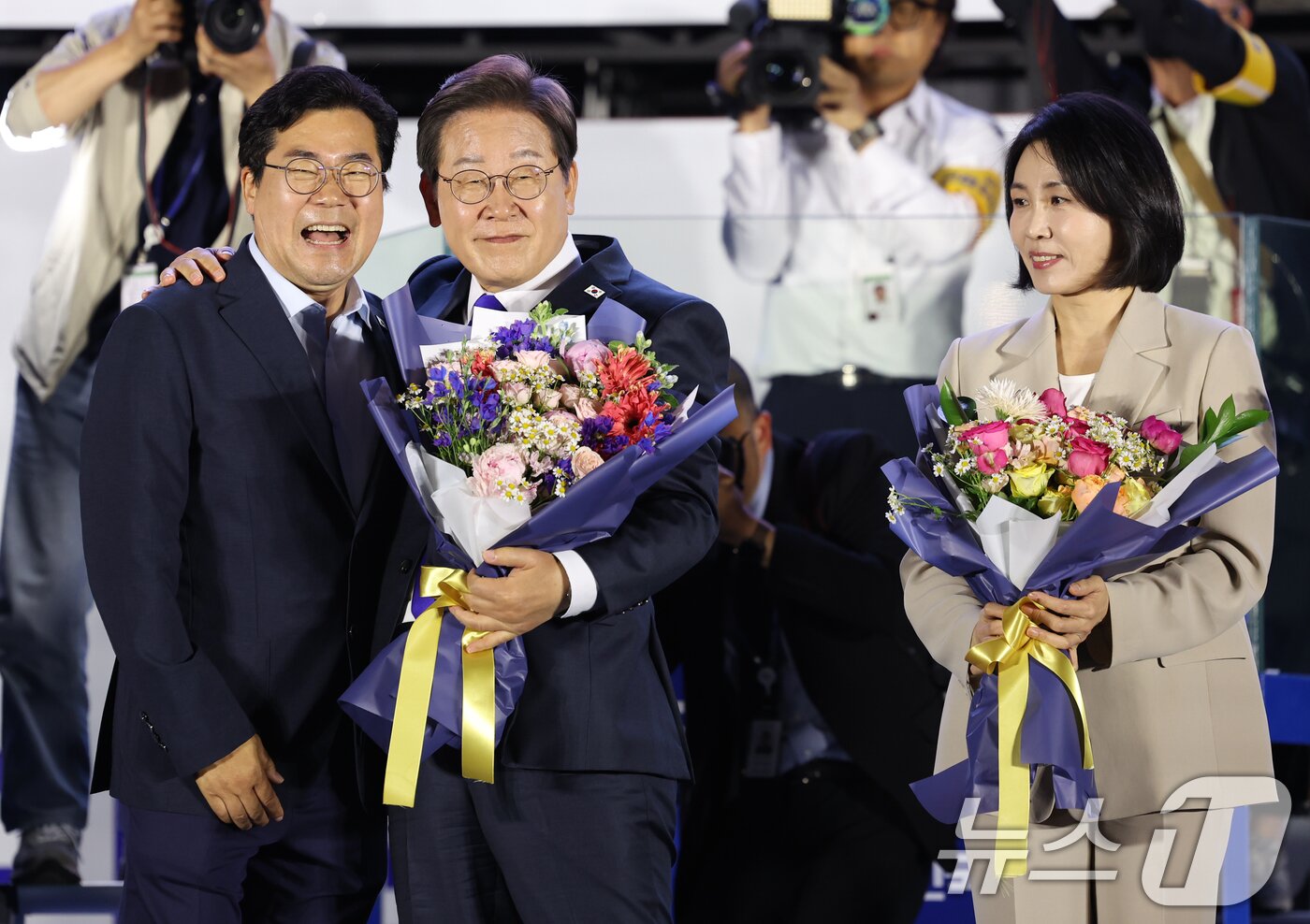 본문 이미지 - 당선이 확실시된 이재명 더불어민주당 대통령 후보가 김혜경 여사와 4일 오전 서울 여의도 국회 앞을 찾아 박찬대 상임총괄선대본부장으로부터 꽃다발을 받고 있다. (공동취재) 2025.6.4/뉴스1 ⓒ News1 안은나 기자