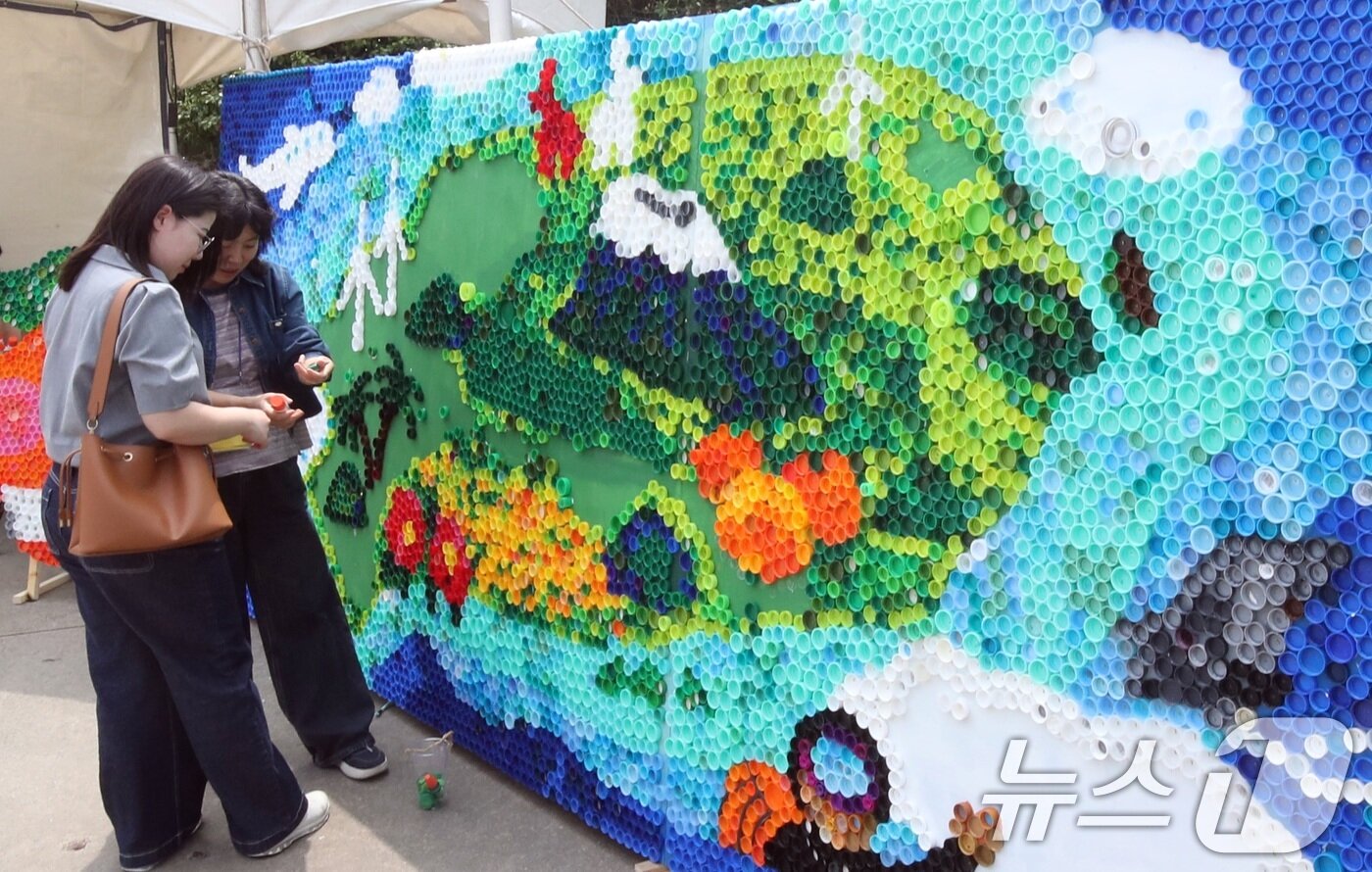 본문 이미지 - 4일 오후 제주 서귀포시 제주국제컨벤션센터 야외광장에서 세계환경의 날을 맞아 열린 &#39;2025 환경 한마당 축제&#39;에서 방문객들이 폐플라스틱 뚜껑으로 만든 제주도 지도를 살펴보고 있다.2025.6.4/뉴스1 ⓒ News1 고동명 기자