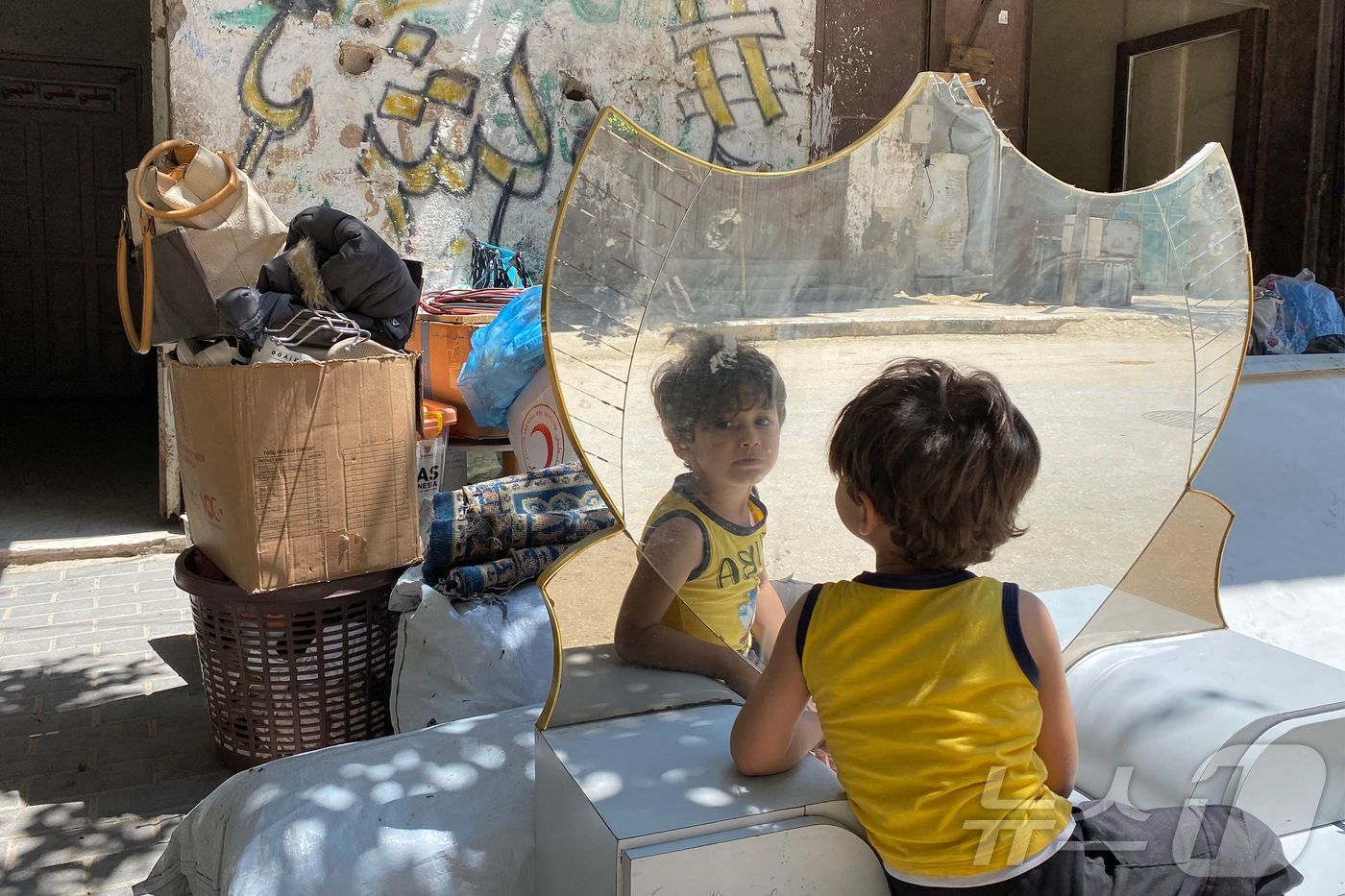 (알마와시 AFP=뉴스1) 권영미 기자 = 3일(현지시간) 가자 지구의 한 어린이가 거울에 비친 자신을 보고 있다. 이 어린이의 가족은 칸유니스에서 더 남쪽인 알마와시로 피난 가기 …