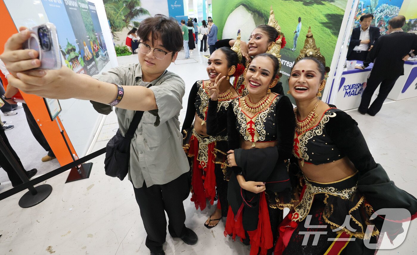 본문 이미지 - 5일 서울 강남구 코엑스에서 열린 제40회 서울국제관광전을 찾은 관람객이 스리랑카 전통복장을 입은 스리랑카관광청 직원들과 기념사진을 찍고 있다. 2025.6.5/뉴스1 ⓒ News1 박세연 기자