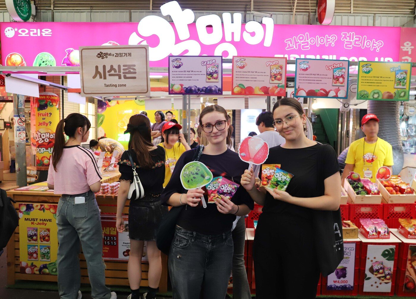 본문 이미지 - 지난 2월 서울 종로구 광장시장에서 열린 '알맹이네 과일가게 시즌2' 팝업스토어에서 외국인 관광객들이 '알맹이' 젤리를 들고 사진을 찍고 있다.(오리온 제공)