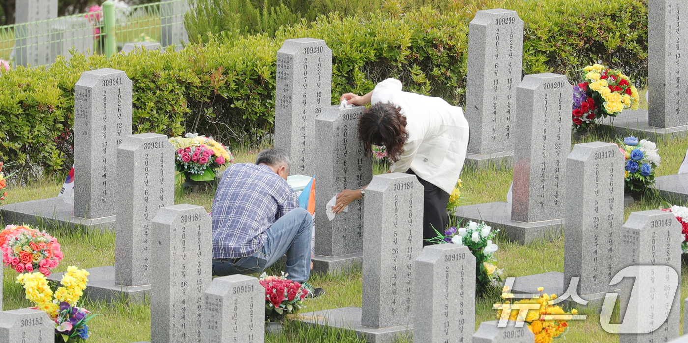 (임실=뉴스1) 유경석 기자 = 현충일인 6일 전북 임실군 국립임실호국원을 찾은 추모객들이 묘비를 닦고 있다. 2025.6.6/뉴스1