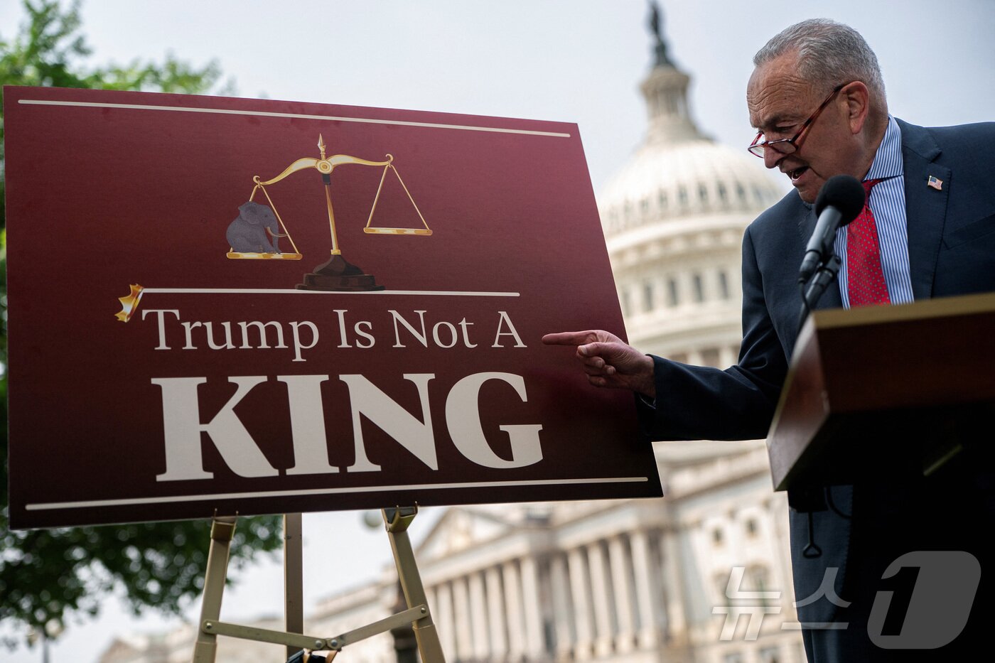 본문 이미지 - 척 슈머 미국 민주당 상원 원내대표가 5일(현지시간) 워싱턴 국회의사당에서 도널드 트럼프 대통령의 감세안 관련 기자회견을 하는 도중에 '트럼프는 왕이 아니다'라고 적힌 패널을 손가락으로 가리키고 있다. 2025.06.05 ⓒ 로이터=뉴스1 ⓒ News1 최종일 선임기자