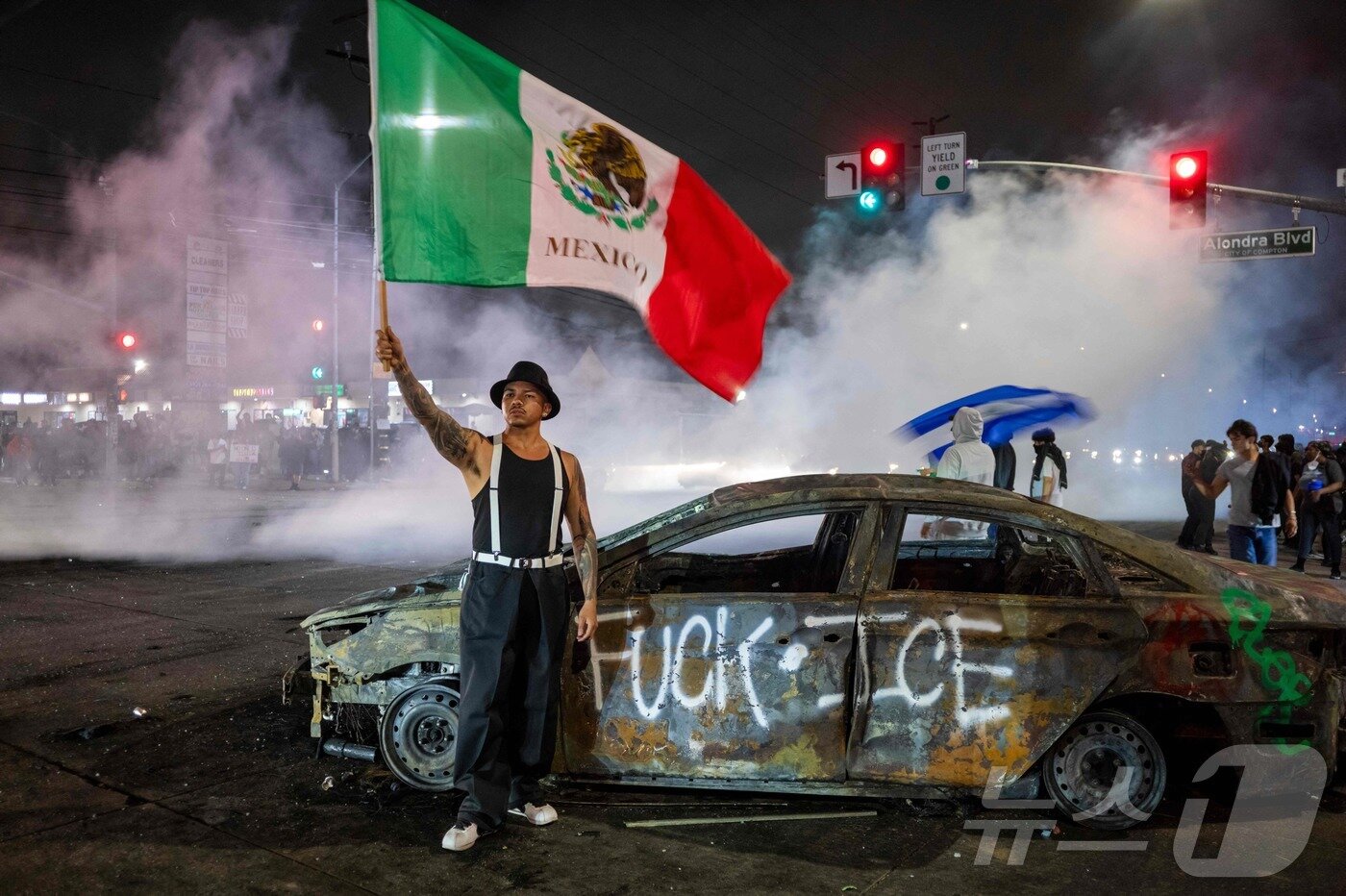 본문 이미지 - 7일(현지시간) 미국 LA에서 열린 연방 이민법 집행 규탄 시위에서 한 시위자가 멕시코 국기를 흔들고 있다.ⓒ AFP=뉴스1