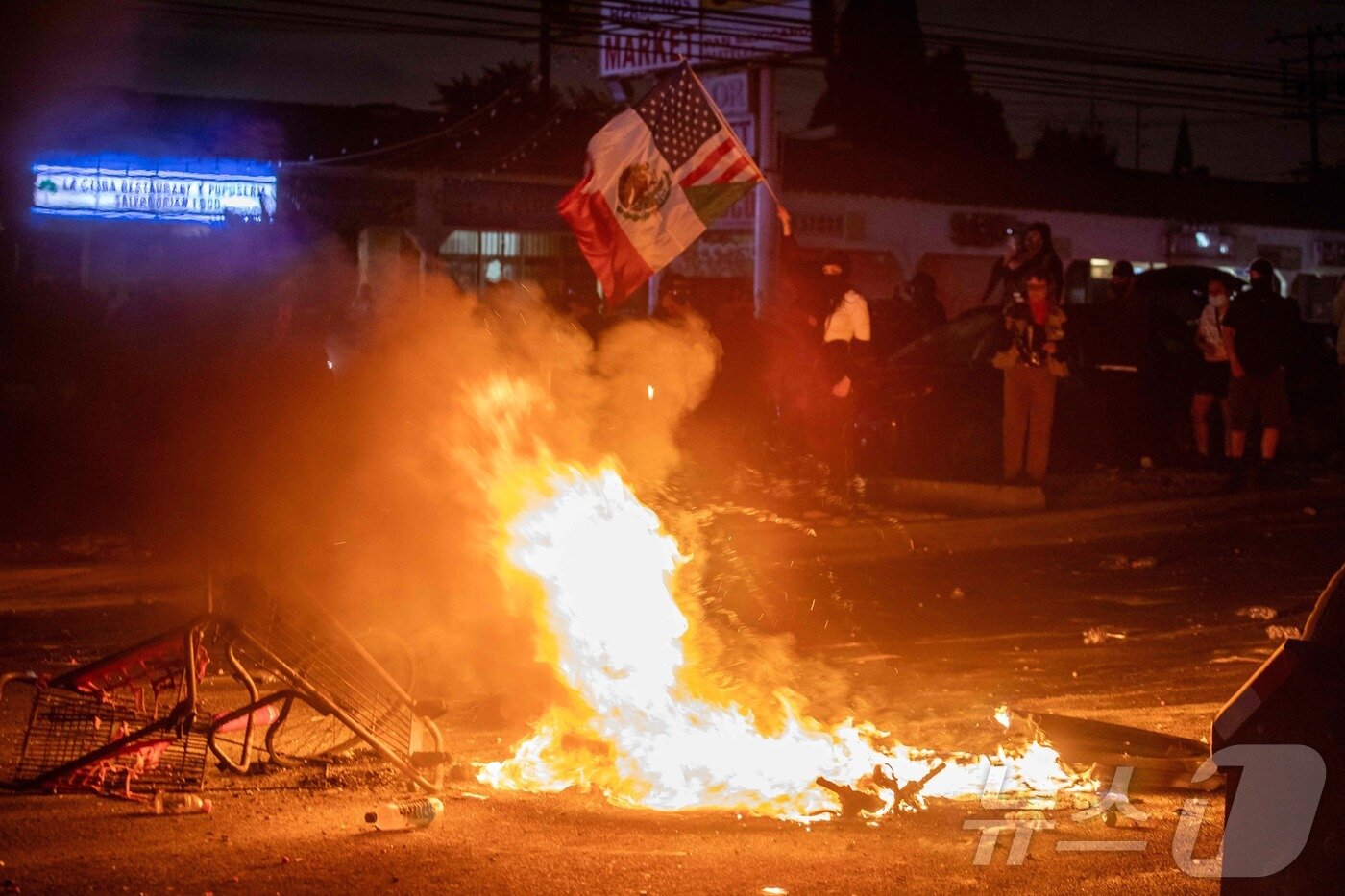 본문 이미지 - 7일(현지시간) 미국 LA에서 열린 연방 이민법 집행에 대한 항의 시위에서 경찰과 시위대가 대치하고 있다.  ⓒ AFP=뉴스1