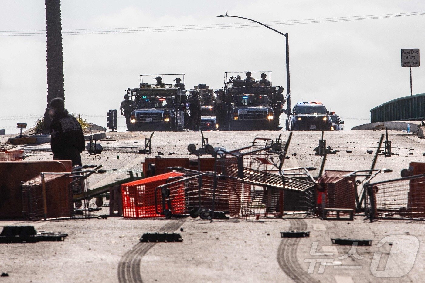 본문 이미지 - 7일(현지시간) 미국 LA 파라마운트 홈디포 인근에서 전술 장비를 갖춘 시위 진압대가 시위대와 대치하고 있다. ⓒ AFP=뉴스1
