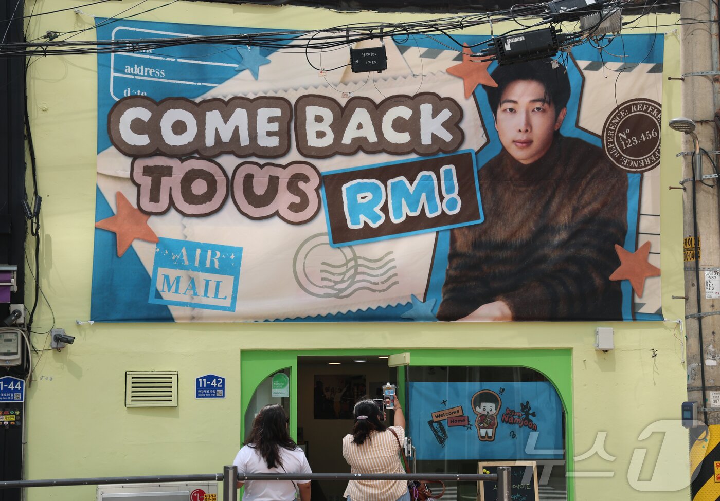 본문 이미지 - 9일 오전 서울 용산구 하이브 사옥 앞에서 방탄소년단(BTS) 글로벌 팬들(아미)이 멤버들의 제대를 기대하며 기념 촬영을 하고 있다.  2025.6.9/뉴스1 ⓒ News1 권현진 기자