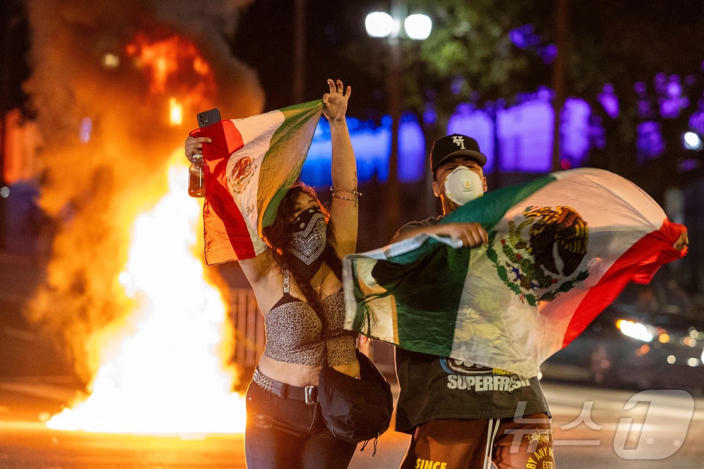 (로스앤젤레스 AFP=뉴스1) 김경민 기자 = 8일(현지시간) 미국 캘리포니아주 로스앤젤레스(LA) 시내에서 연방 이민 단속에 반대하는 시위 중 시위대가 멕시코 국기를 들고 있다. …