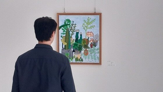 본문 이미지 -  휴젤 사내에 전시된 장애예술인들의 작품을 임직원이 감상하고 있다. &#40;휴젤 제공&#41;