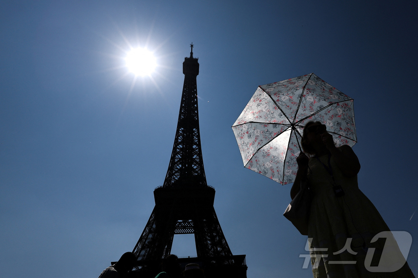 (파리 로이터=뉴스1) 김경민 기자 = 프랑스 파리에 있는 에펠탑 앞에 한 관광객이 양산을 들고 서있다. 2025.6.19ⓒ 로이터=뉴스1